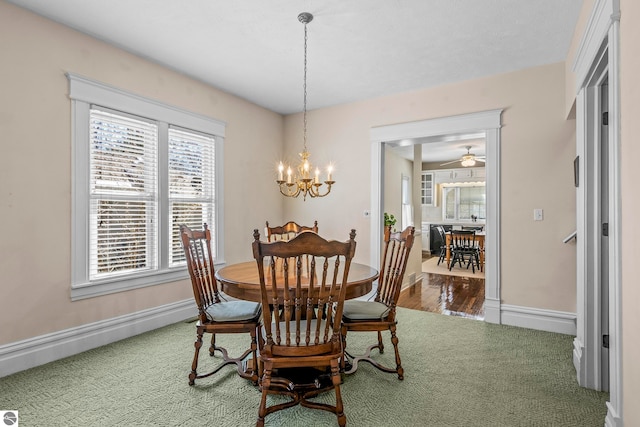 carpeted dining area with baseboards, wood finished floors, and ceiling fan with notable chandelier