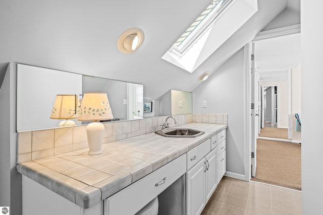 bathroom with decorative backsplash, baseboards, vanity, and lofted ceiling with skylight