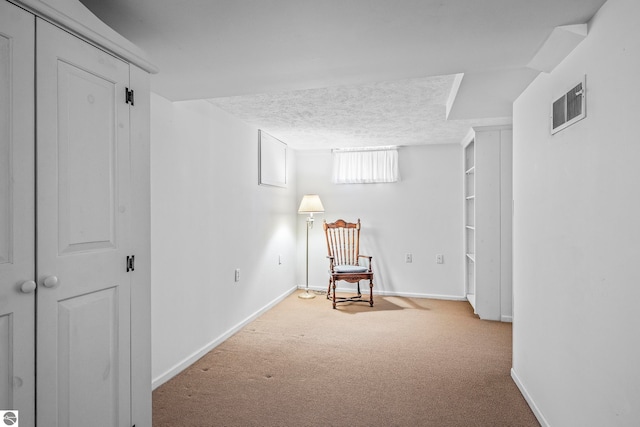 unfurnished room with carpet floors, a textured ceiling, visible vents, and baseboards