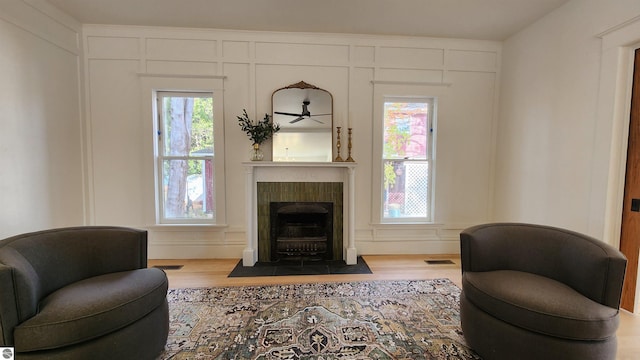 living area featuring a tiled fireplace, wood finished floors, and plenty of natural light