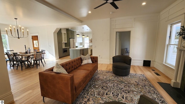living area featuring ceiling fan with notable chandelier, light wood-style flooring, arched walkways, and recessed lighting