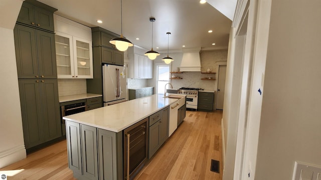 kitchen with stainless steel appliances, wine cooler, a sink, light wood-style floors, and open shelves