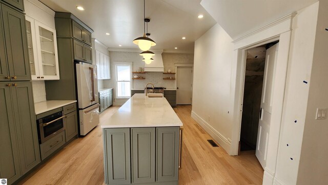 kitchen with freestanding refrigerator, light wood-type flooring, stainless steel oven, and visible vents