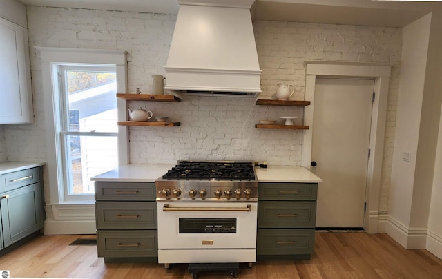 kitchen featuring open shelves, light countertops, gas stove, and custom range hood