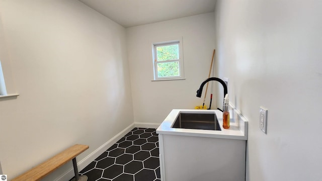 laundry room with dark tile patterned flooring, baseboards, and a sink