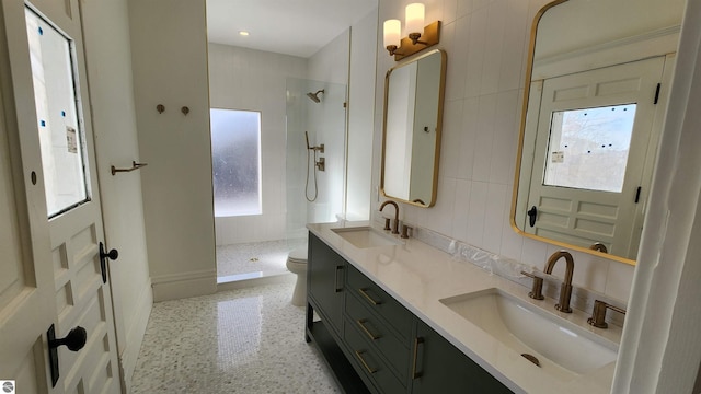 bathroom with a tile shower, double vanity, and a sink