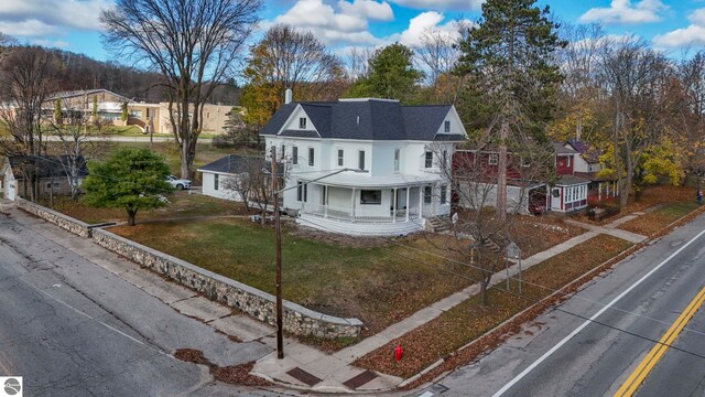 view of front facade featuring driveway, covered porch, a front yard, and a residential view