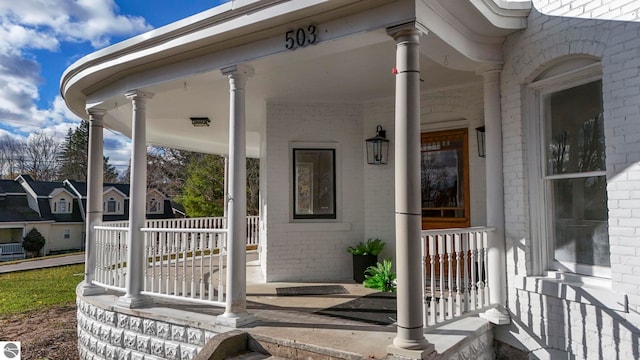 doorway to property with brick siding and covered porch