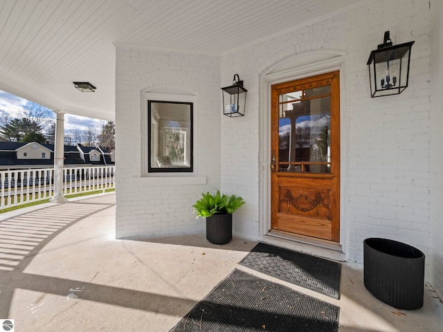 doorway to property featuring brick siding and a porch