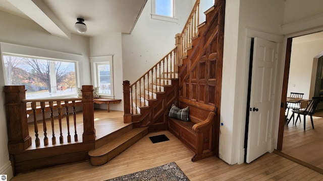 stairs with hardwood / wood-style flooring, a high ceiling, and a healthy amount of sunlight