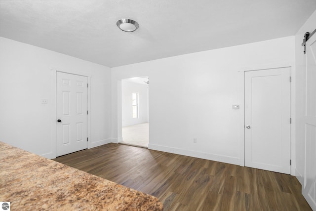 419 S Cherry St, Kalkaska, MI 49646 - empty room with baseboards, dark wood-style flooring, and a barn door