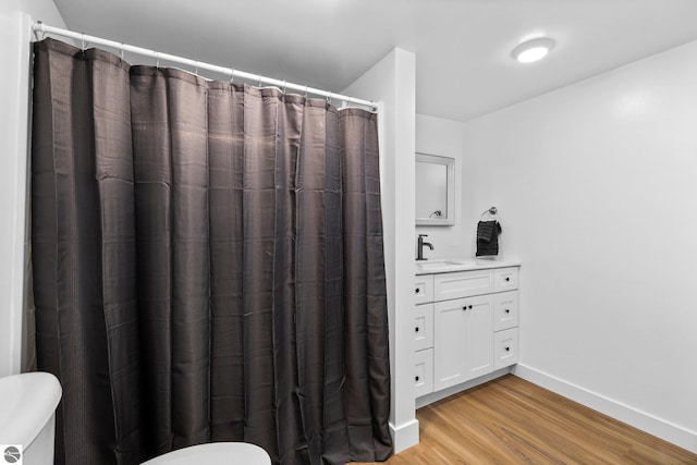 419 S Cherry St, Kalkaska, MI 49646 - full bathroom with a shower with curtain, toilet, baseboards, wood finished floors, and vanity
