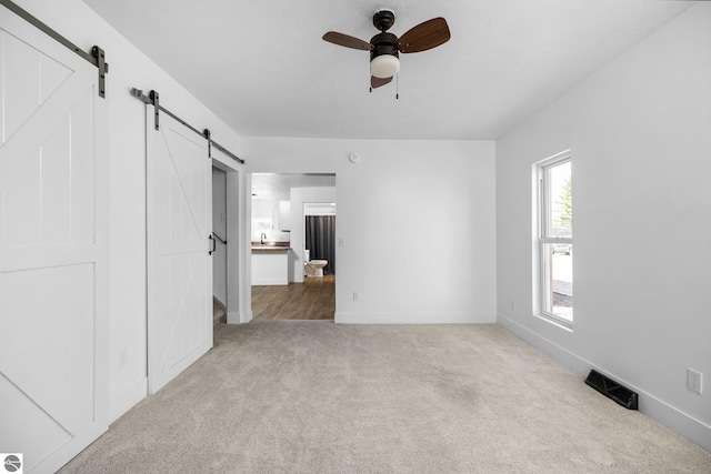 419 S Cherry St, Kalkaska, MI 49646 - unfurnished bedroom featuring baseboards, visible vents, carpet, and a barn door