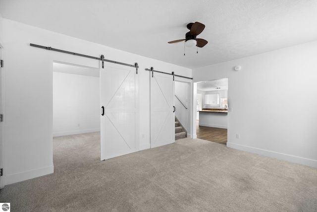 419 S Cherry St, Kalkaska, MI 49646 - interior space with a barn door, carpet floors, ceiling fan, and baseboards