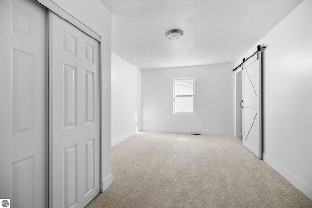419 S Cherry St, Kalkaska, MI 49646 - unfurnished bedroom with baseboards, carpet floors, and a barn door