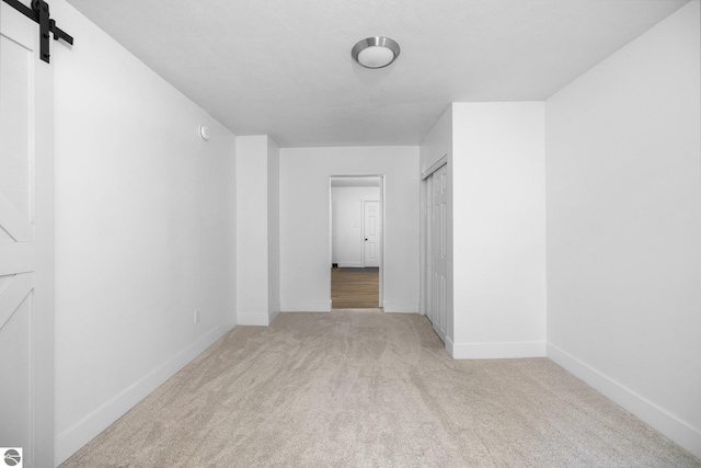 419 S Cherry St, Kalkaska, MI 49646 - carpeted empty room featuring a barn door and baseboards