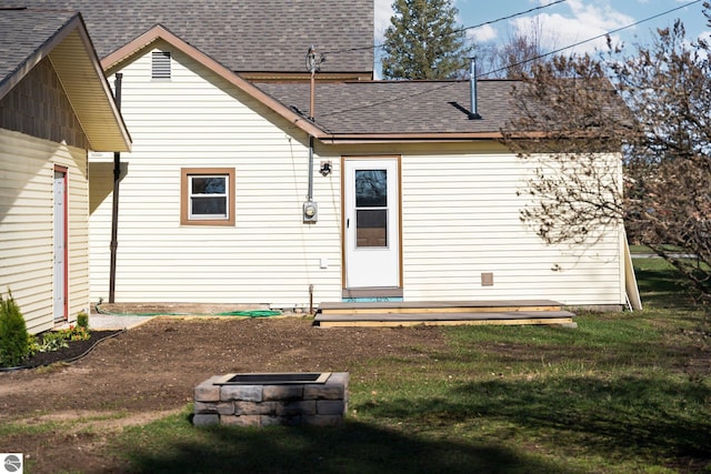 419 S Cherry St, Kalkaska, MI 49646 - back of property featuring roof with shingles, an outdoor fire pit, and a lawn