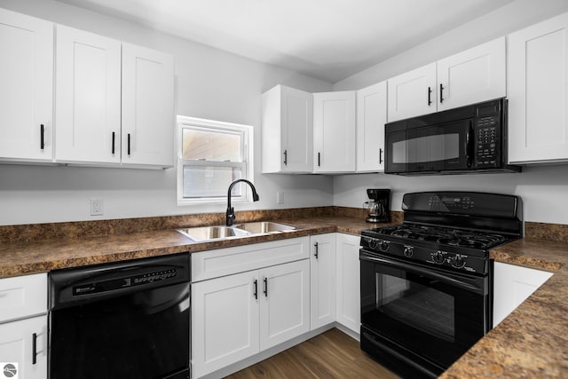 419 S Cherry St, Kalkaska, MI 49646 - kitchen with dark countertops, white cabinetry, a sink, and black appliances
