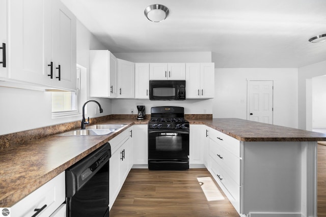 419 S Cherry St, Kalkaska, MI 49646 - kitchen featuring dark countertops, a sink, dark wood-type flooring, black appliances, and a peninsula