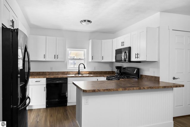 419 S Cherry St, Kalkaska, MI 49646 - kitchen featuring a peninsula, dark wood-style floors, a sink, dark countertops, and black appliances