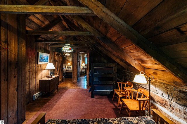 interior space with lofted ceiling with beams, wooden ceiling, wood walls, and visible vents