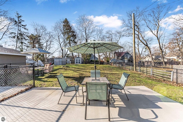 view of patio / terrace with a residential view, a storage shed, a fenced backyard, an outbuilding, and outdoor dining area