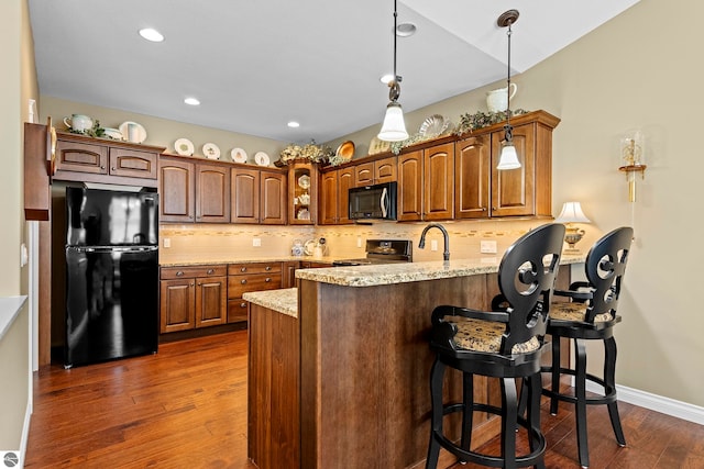 4584 Kodiak Dr, Traverse City, MI 49685 - kitchen with a peninsula, backsplash, dark wood-type flooring, and black appliances