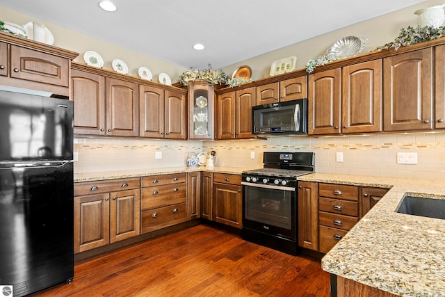 4584 Kodiak Dr, Traverse City, MI 49685 - kitchen with dark wood-style floors, light stone counters, black appliances, and tasteful backsplash