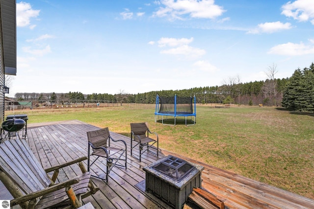 5891 Voice Rd, Kingsley, MI 49649 - deck featuring a lawn, a fire pit, and a trampoline