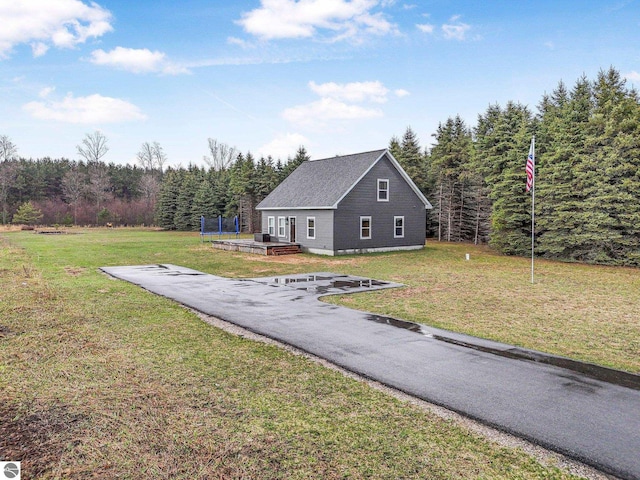 5891 Voice Rd, Kingsley, MI 49649 - view of front facade with a wooden deck, a forest view, and a front yard