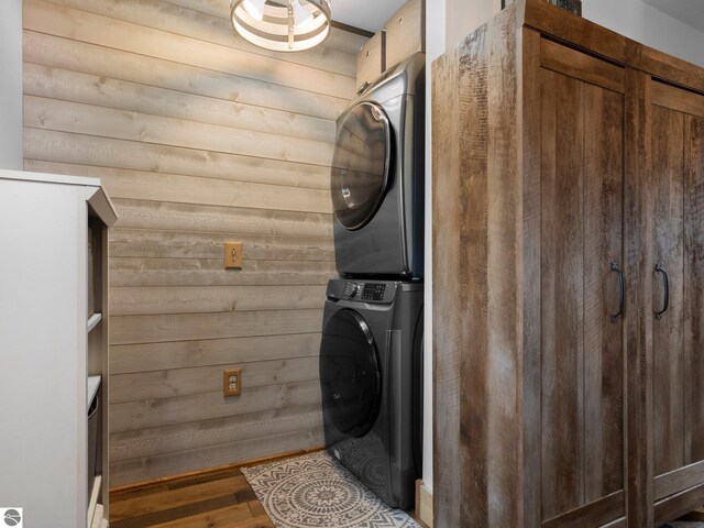 5242 W Big Sky Trl, Cadillac, MI 49601 - clothes washing area with stacked washer and clothes dryer, wooden walls, and wood finished floors