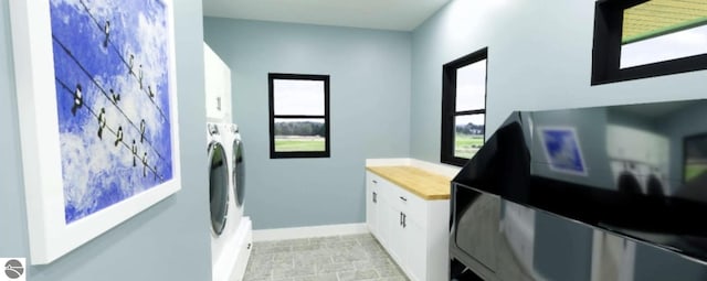 clothes washing area featuring cabinet space, independent washer and dryer, and baseboards