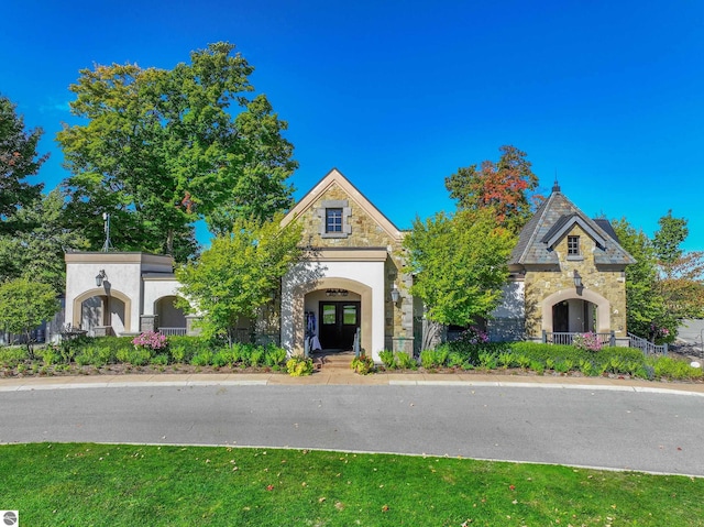 view of front of house featuring stone siding, french doors, and stucco siding