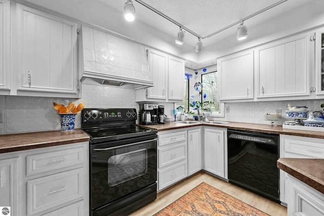 kitchen with black appliances, decorative backsplash, a sink, and white cabinets