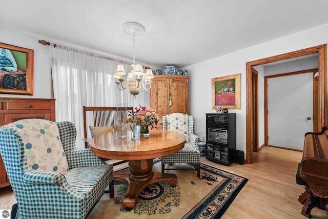 dining area with light wood finished floors and a notable chandelier