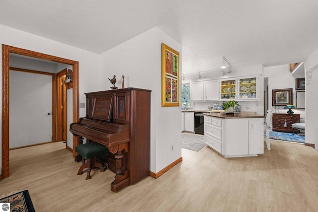 kitchen with dishwasher, baseboards, light wood-style floors, and white cabinetry