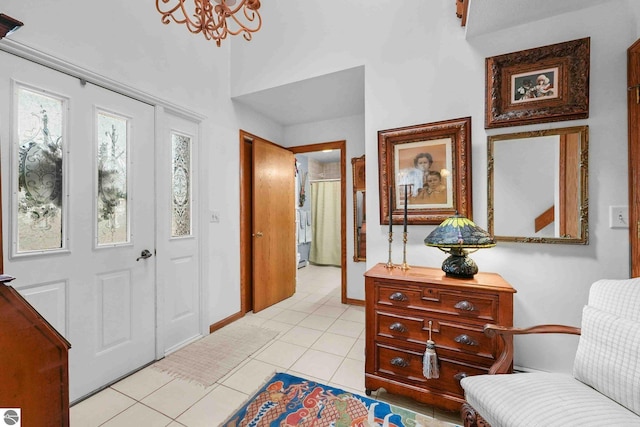 foyer entrance with baseboards, a chandelier, and light tile patterned floors
