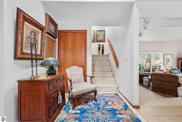 sitting room with baseboards, carpet floors, and stairs