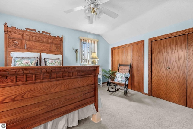 bedroom featuring vaulted ceiling, multiple closets, a ceiling fan, and light carpet