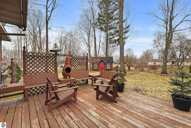 wooden deck featuring a storage shed, an outbuilding, and a lawn