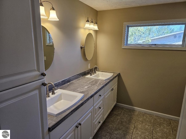 bathroom featuring a sink, baseboards, tile patterned flooring, and double vanity