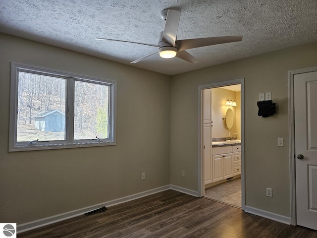 unfurnished bedroom featuring dark wood-style flooring, baseboards, visible vents, and a textured ceiling