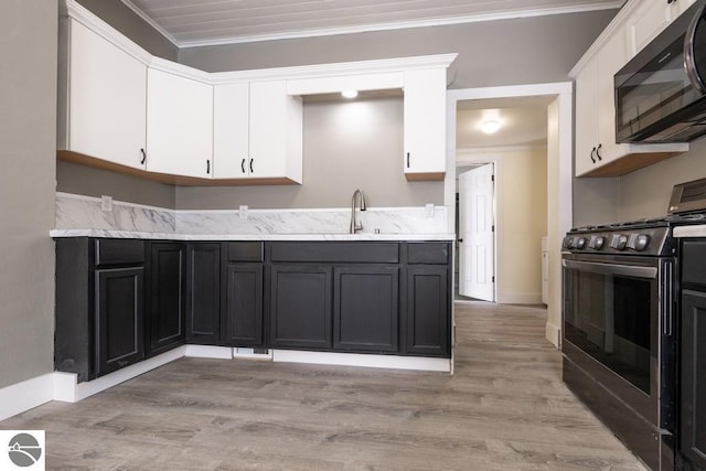 kitchen with a sink, black microwave, white cabinetry, stainless steel gas stove, and ornamental molding