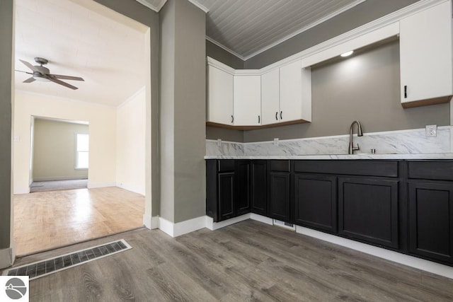 kitchen featuring ceiling fan, light wood-style flooring, white cabinets, ornamental molding, and visible vents