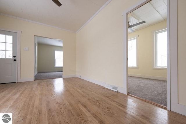 foyer entrance with visible vents, wood finished floors, ornamental molding, and ceiling fan