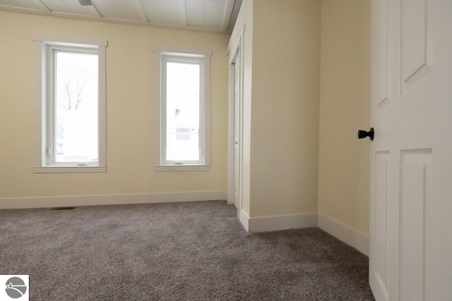 carpeted empty room featuring baseboards and a healthy amount of sunlight