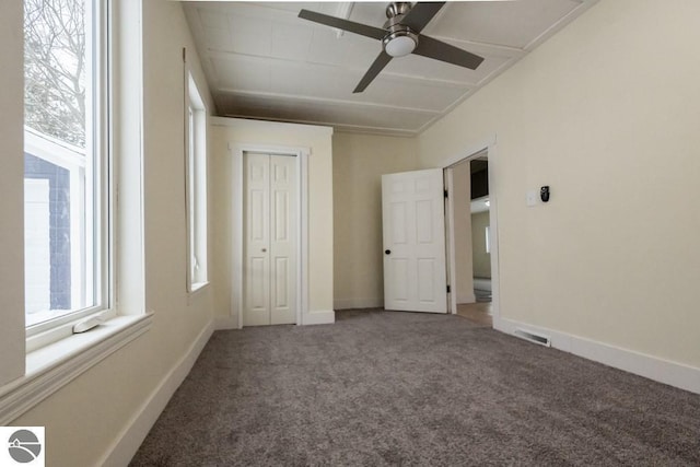 unfurnished bedroom with a closet, ceiling fan, carpet, baseboards, and visible vents