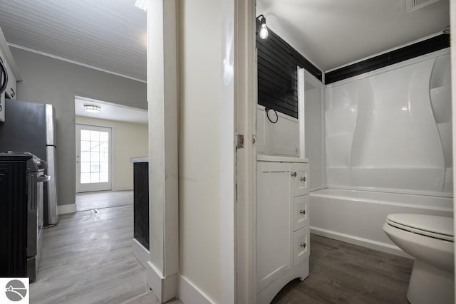 full bathroom with wood finished floors, vanity, a fireplace, toilet, and bathing tub / shower combination