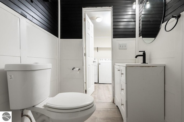 bathroom featuring wood finished floors, independent washer and dryer, vanity, and toilet