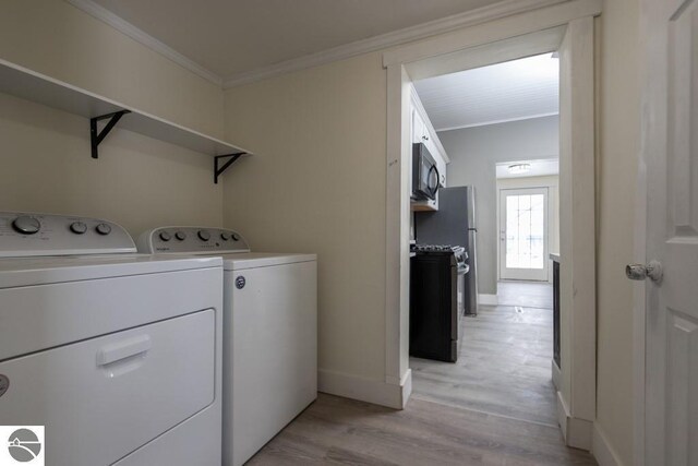 washroom featuring washing machine and clothes dryer, light wood finished floors, baseboards, crown molding, and laundry area
